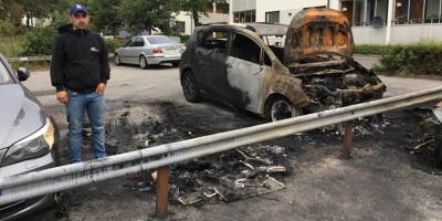 Hasan Tümtürk stands in front of his and other cars damaged by fire at a parking lot.