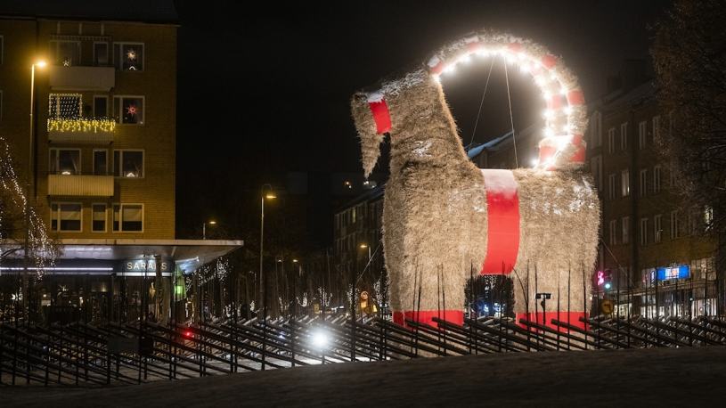 A giant, lit-up straw goat surrounded by a fence in the city centre of Gävle, Sweden.